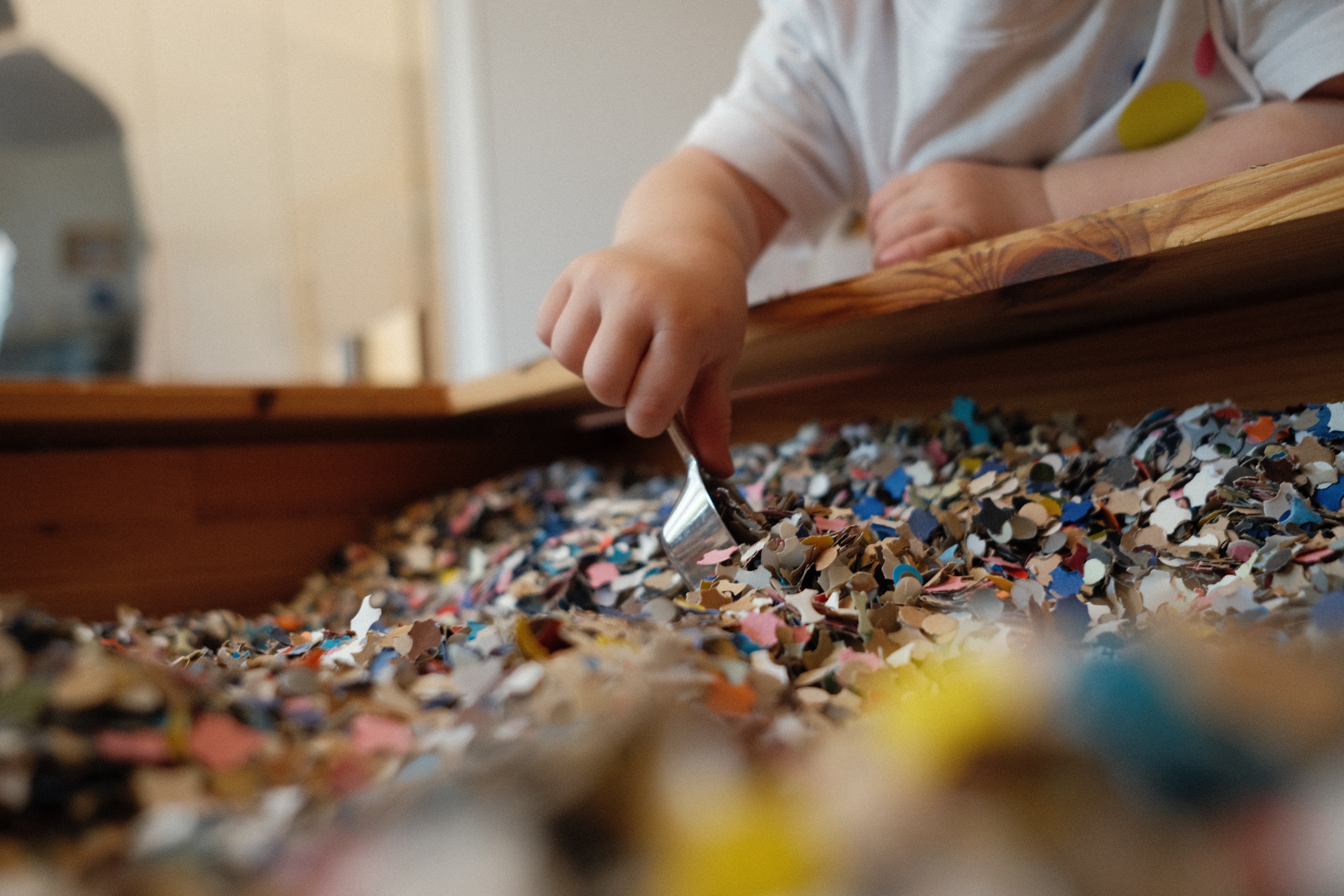A child is scooping up scraps of paper from a large box