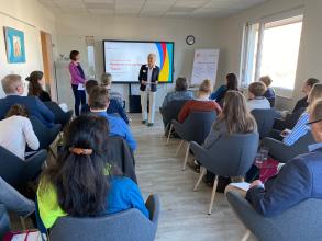 
		A speaker stands in front of the seated audience
	