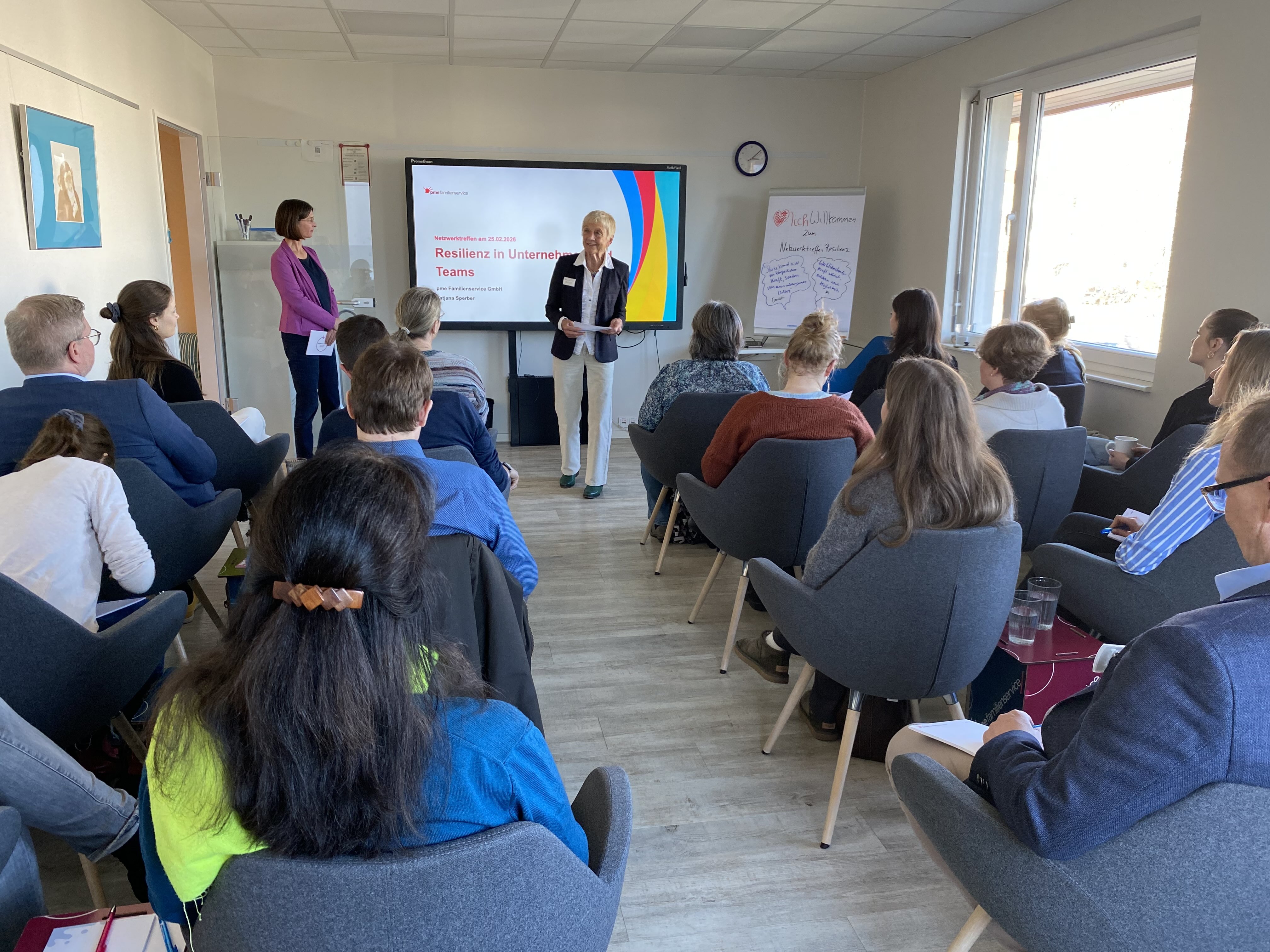 A speaker stands in front of the seated audience