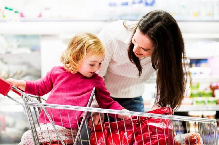 The picture shows a woman and a small child in a shopping cart
