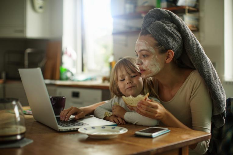 A woman is sitting in front of a laptop with a toddler