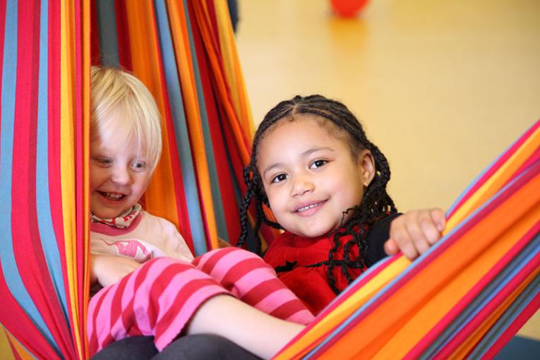 Two children are lying in a hammock
