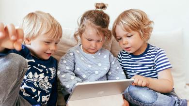 
		Three children look into a tablet
	