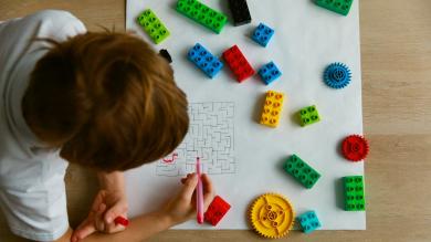 
		Boy sits at desk and solves maze
	