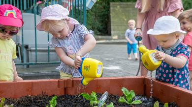 
		Young children watering a raised bed
	