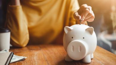 
		Woman throws coins into a piggy bank
	