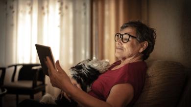 
		Elderly woman looks into tablet
	