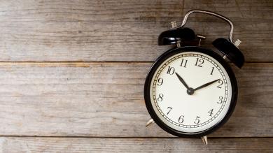 
		Old-fashioned alarm clock in front of a wooden wall
	