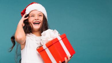 
		Cheerful girl with Santa hat and gift
	