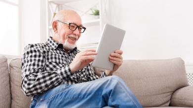 
		Elderly man happily looking into a tablet
	