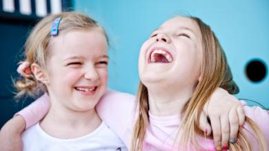 
		Two laughing little girls hugging each other
	