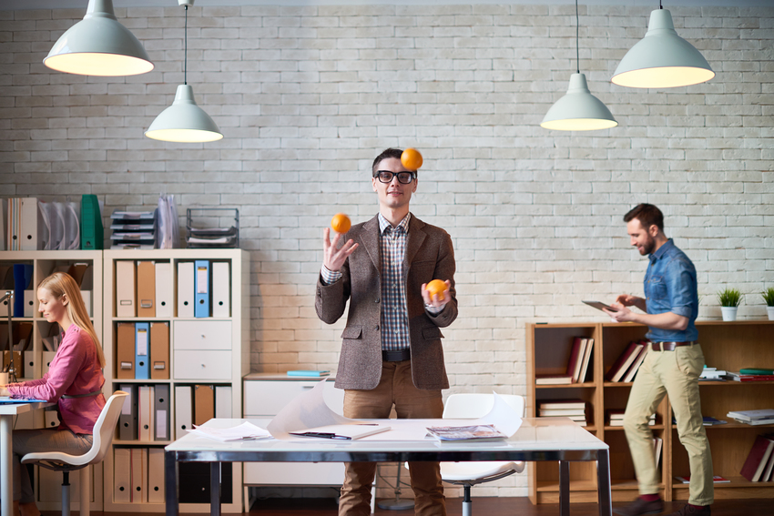 A man juggles with fruit in the office