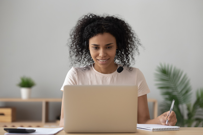 Frau blickt in die Kamera eines Laptops