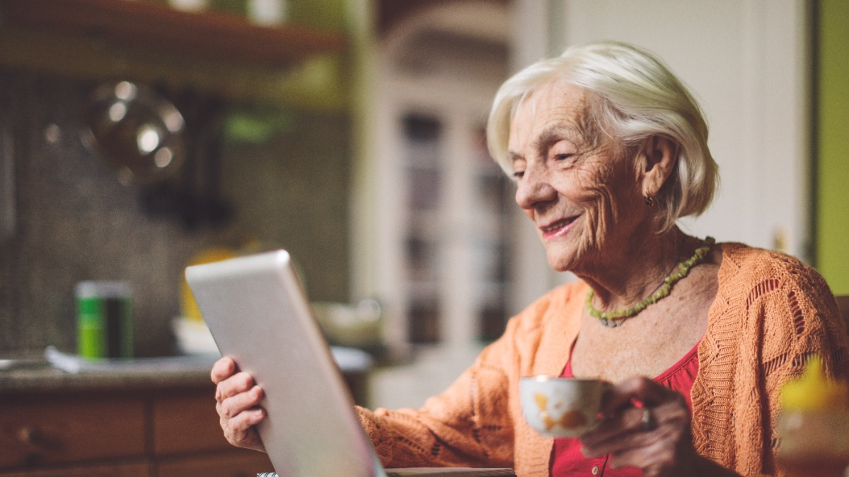 Old lady looks contentedly into a tablet