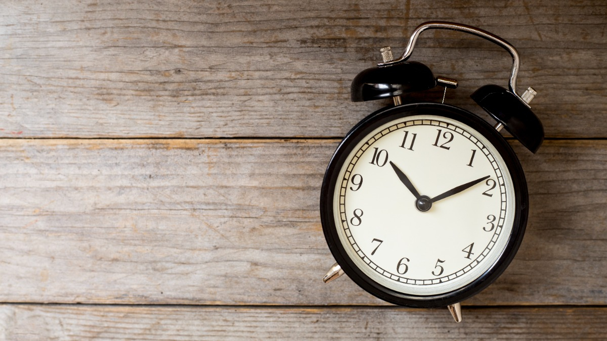 Old-fashioned alarm clock in front of a wooden wall