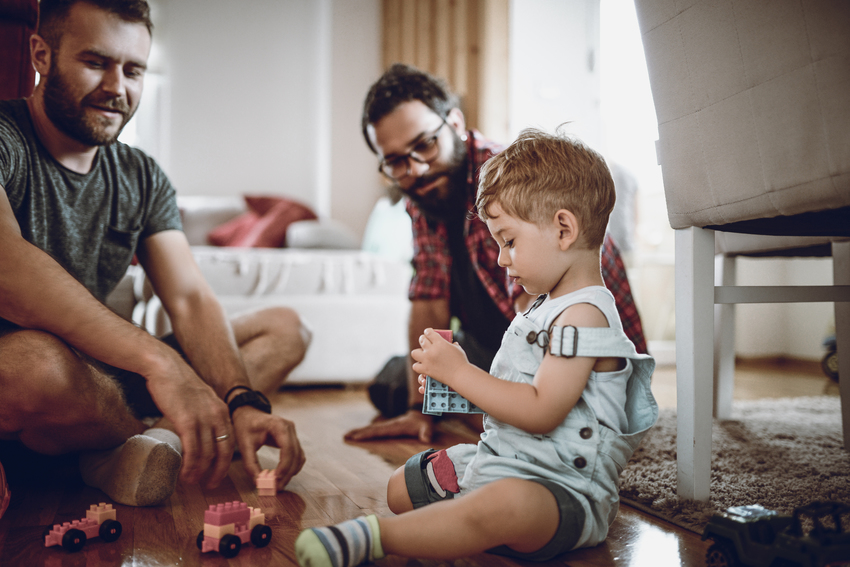 Homosexual couple with daughter sit in a children's room and play with each other