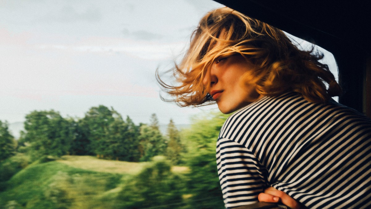 Young woman looks confidently out of a train window