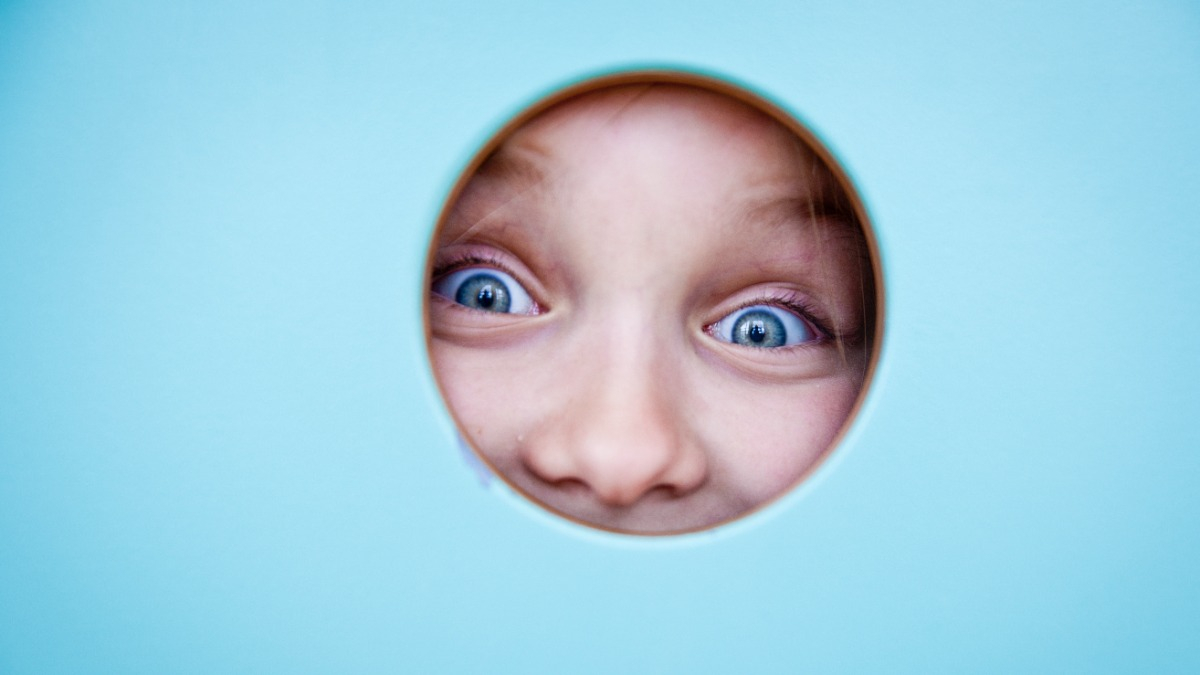 Kindergarten child looks through a peephole