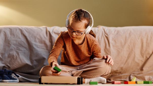 
		A child wearing headphones is sitting on the floor and playing
	