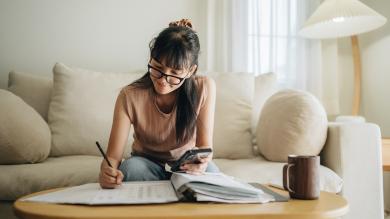 
		A woman sits at the table and does the math - parental allowance reform 2024
	