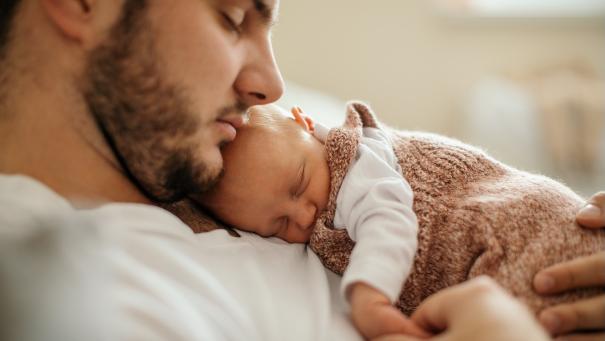 
		Father sleeps with baby in his arms
	