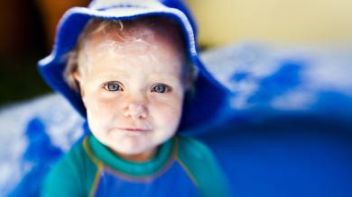 
		Little girl with sunscreen on her face laughs
	