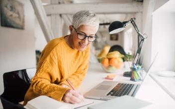
		Older woman at the desk is happy and makes a note of something
	