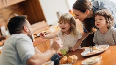 
		A family sits at the kitchen table and eats together
	