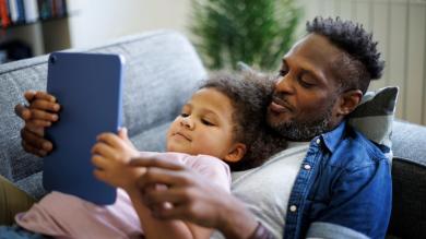 
		Father and child look at an Ipad together
	