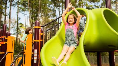 
		A girl is sliding down a green slide
	