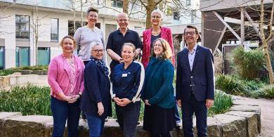 
		A compatibility guide pushes a senior citizen in a wheelchair, who laughs and throws his arms up in the air.
	