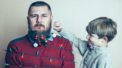 
		Young father under stress is hung with Christmas decorations by child
	