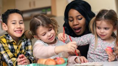 
		Childcare worker with children painting
	