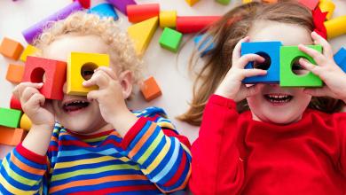 
		Two children are looking through colorful building blocks
	