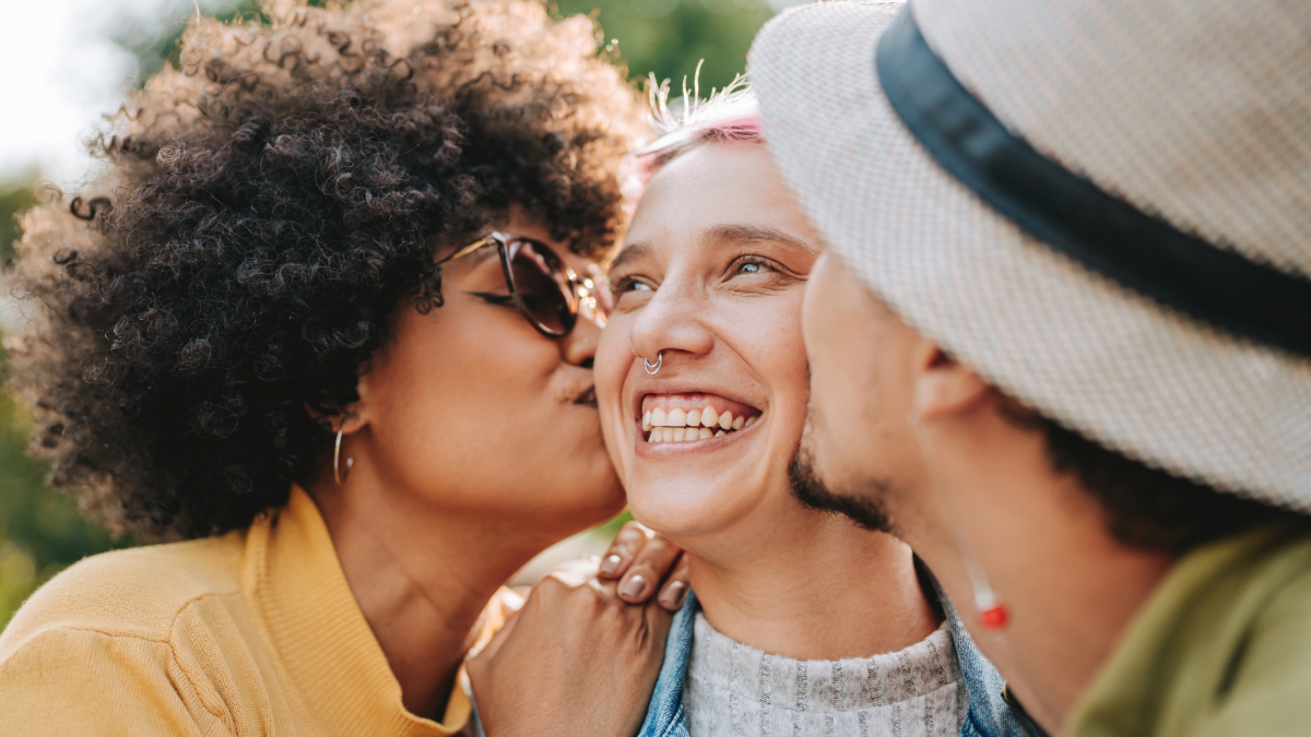 Two girlfriends kissing a girlfriend on the cheeks