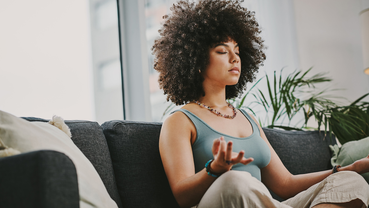 A woman sits on the sofa and does mudra finger yoga