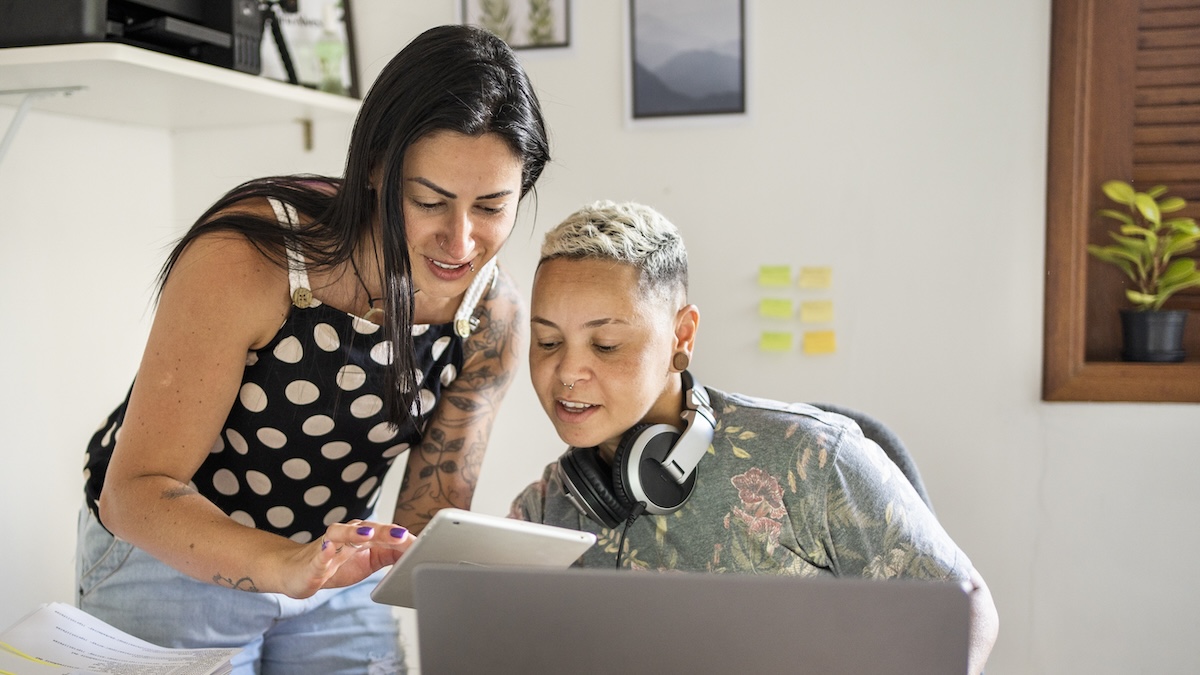 Two women look at a laptop and fill out an application