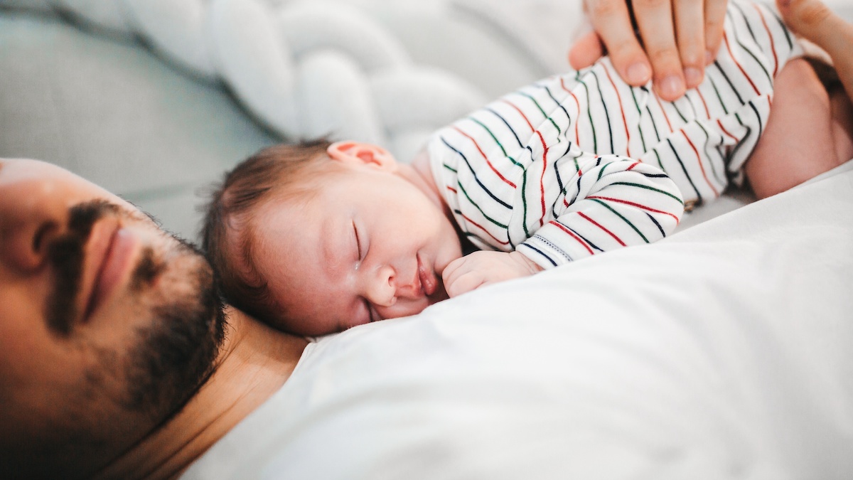 A baby sleeps on its father's chest