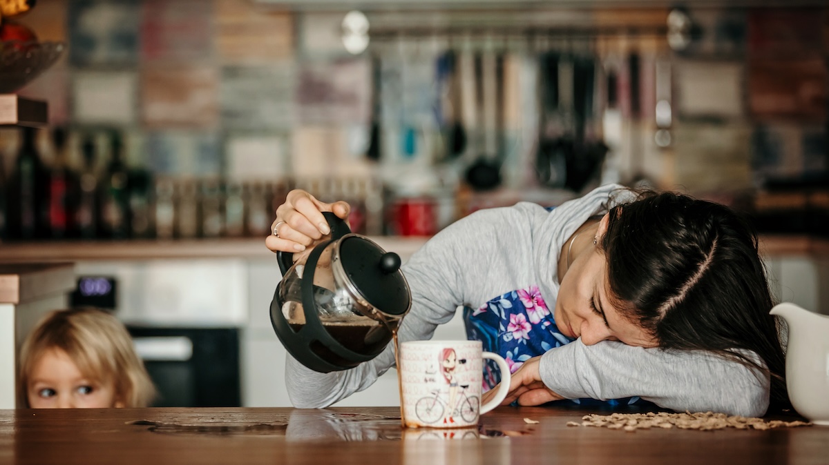A tired woman with her head on the table pours coffee into the pot