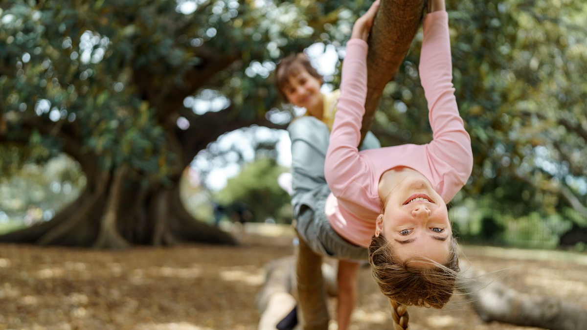 A girl hangs upside down from a tree