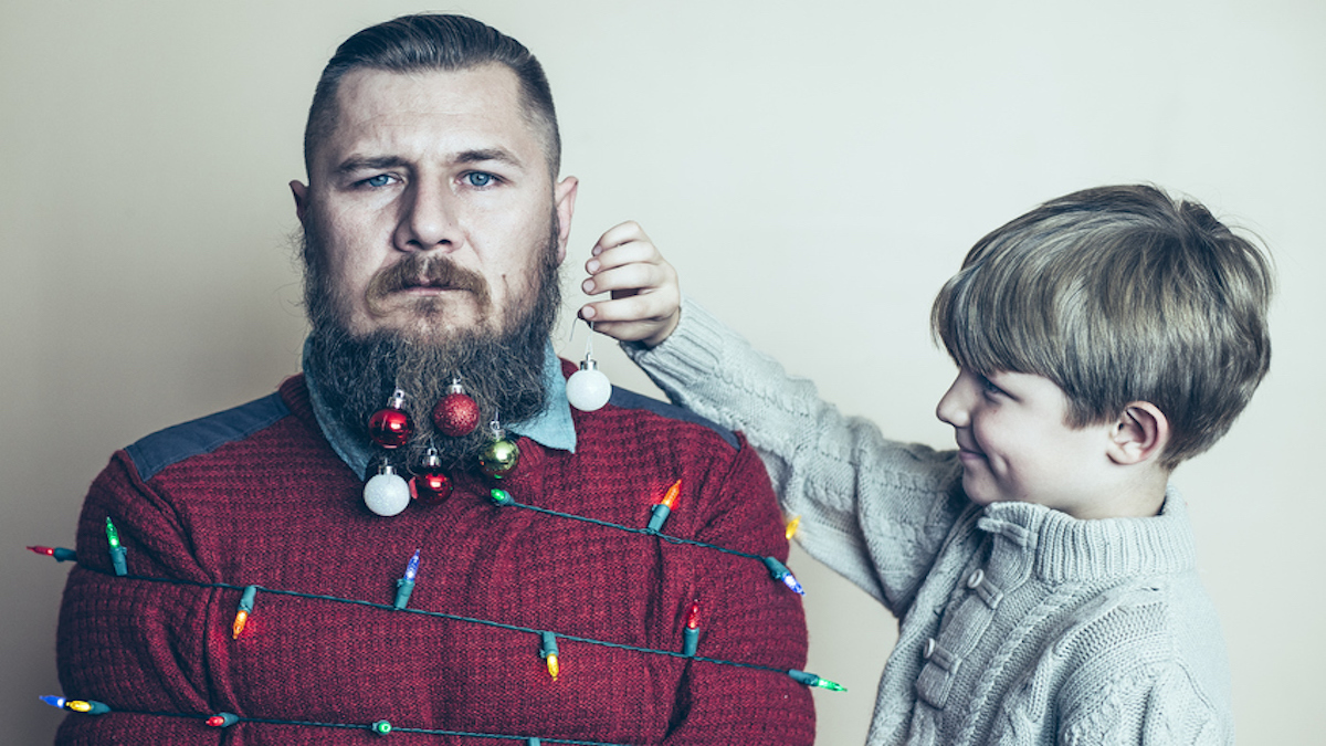 Young father under stress is hung with Christmas decorations by child