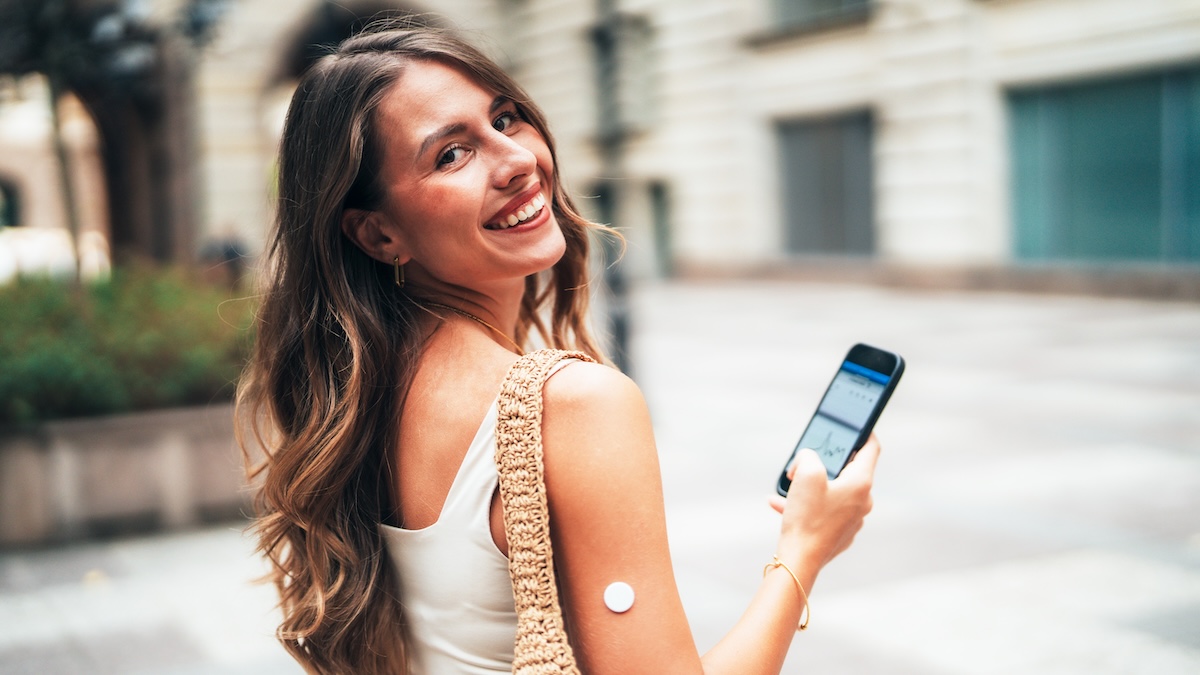 Young woman with a CGM sensor and a cell phone
