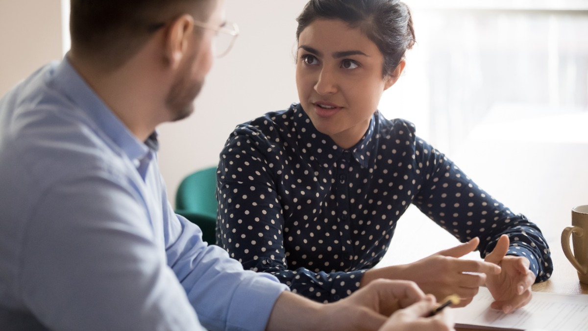 Junge Frau spricht im Büro mit jungem Mann