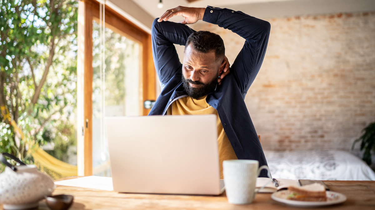 Man at desk stretches neck