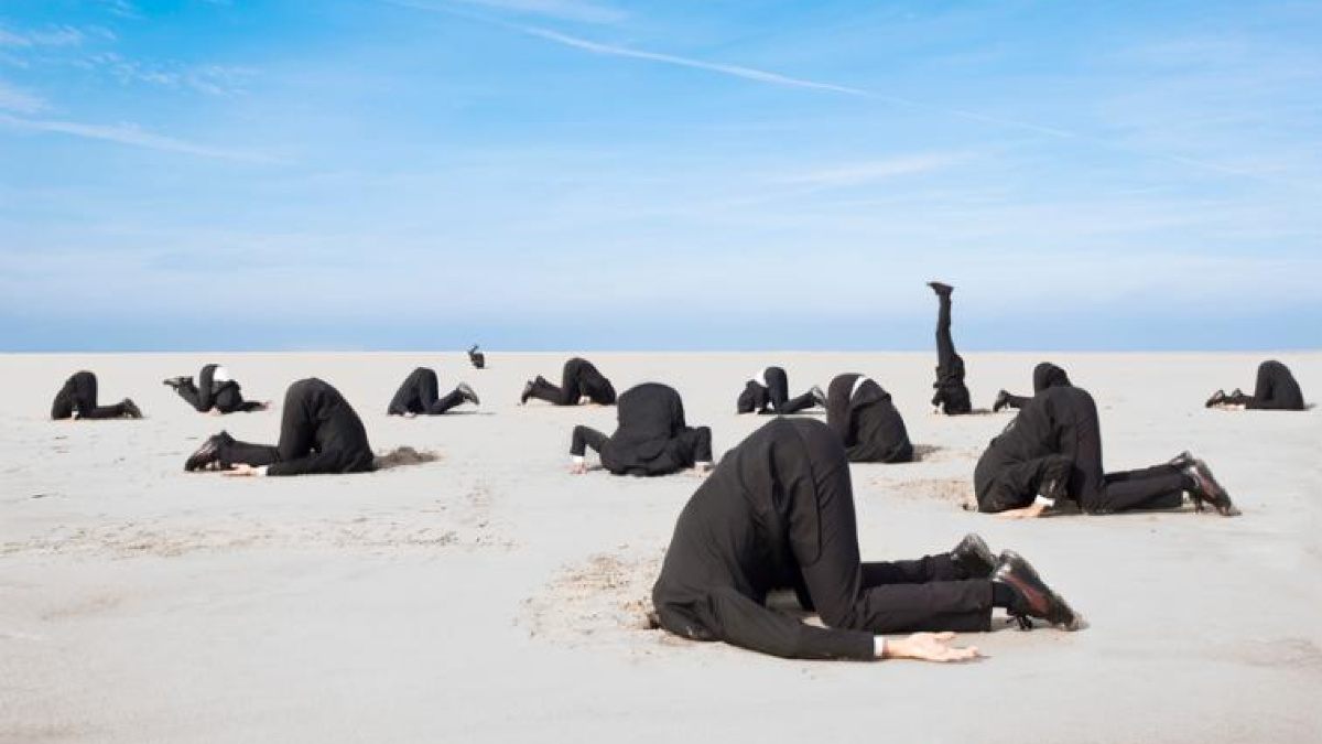 Men in suits bury their heads in the sand