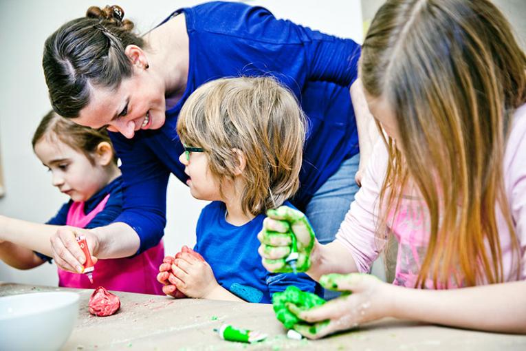 Children knead happily together with an educator