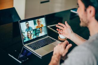 Man sits in front of a laptop and communicates with colleagues via video